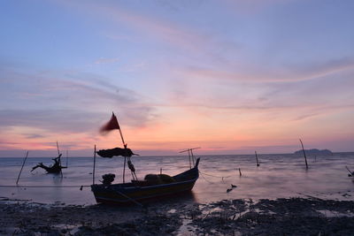 Silhouette boat on beach against sky during sunset