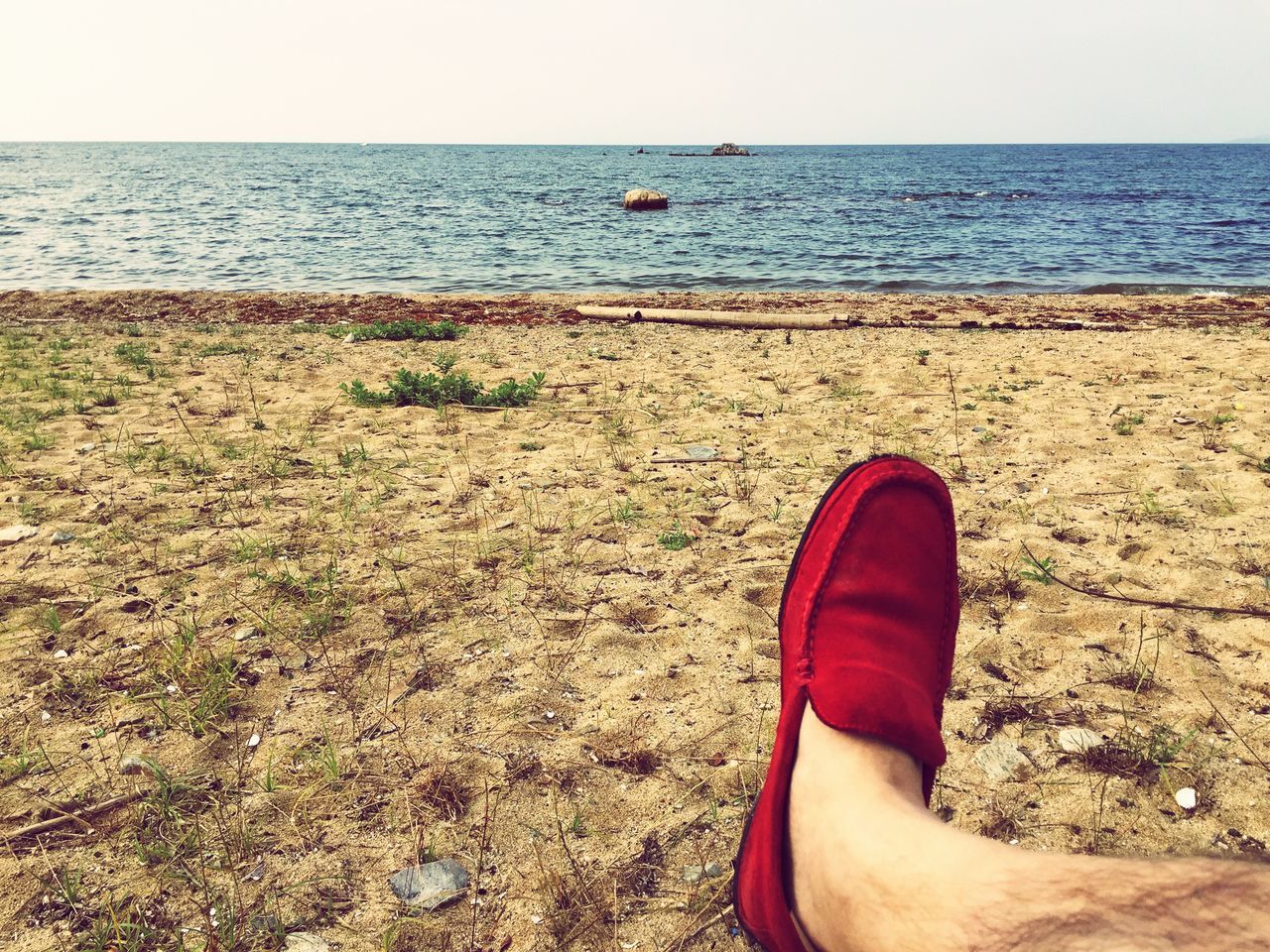 LOW SECTION OF PERSON ON BEACH AGAINST SKY