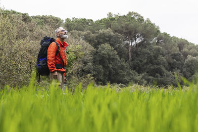 Senior man looking up while standing in grass