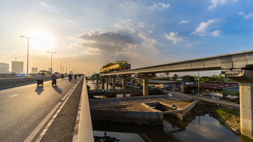 Bridge over road against sky during sunset