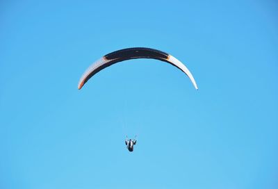 Low angle view of person paragliding against clear blue sky