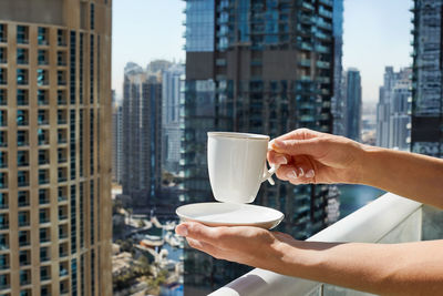 A girl holds a cup of coffee against the background 