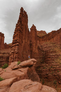 Hiker stands under fisher towers on a hike outside of moab utah