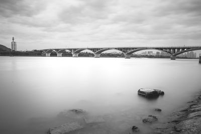 Bridge over river against cloudy sky