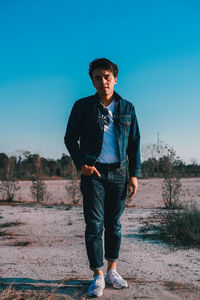 Portrait of young man standing on land against sky