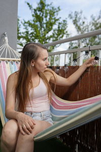 Young woman looking away while sitting on railing