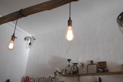 Illuminated light bulb hanging on wall at home
