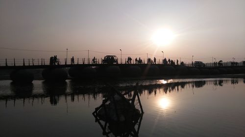 People walking on bridge at sunset