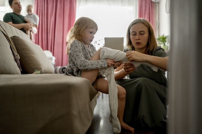 Mother helping daughter putting on tights at home