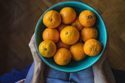 A mother and son place organic oranges in a green bowl.