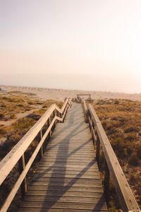 Boardwalk on footbridge against clear sky