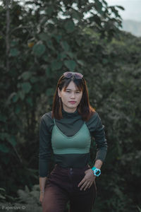 Portrait of beautiful young woman against plants