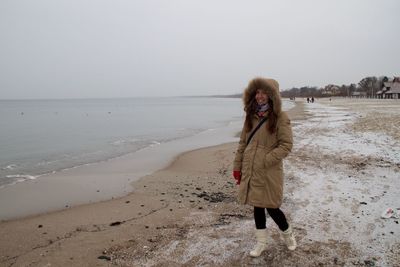 Portrait of woman standing on sand at beach during winter