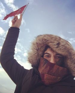 Low angle portrait of woman against sky during winter