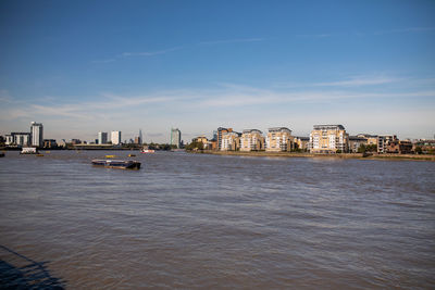 Sea by buildings against sky in city