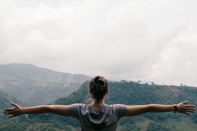 Rear view of woman standing on mountain against sky