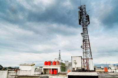 Low angle view of communications tower against cloudy sky