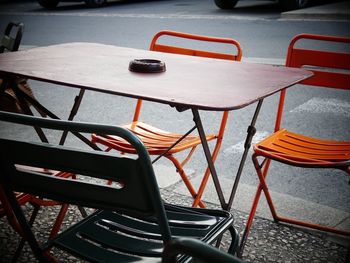 Close-up of empty chairs and table at sidewalk cafe