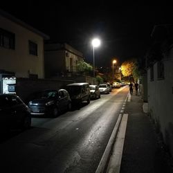 Cars on road by illuminated buildings in city at night