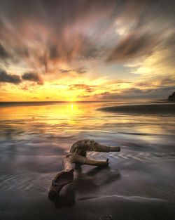 Scenic view of sea against dramatic sky during sunset