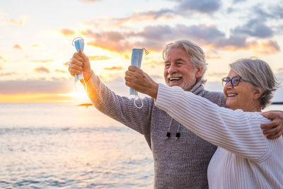 People photographing at beach against sky