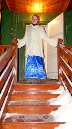Portrait of happy woman in warm cloth standing on steps during winter at night
