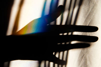Close-up of silhouette hand by curtain
