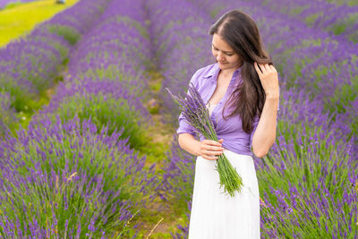 Woman standing by purple flowers on field