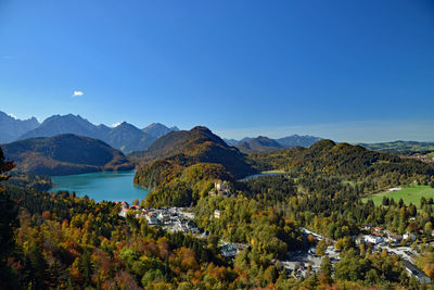 Scenic view of lake and mountains against clear blue sky