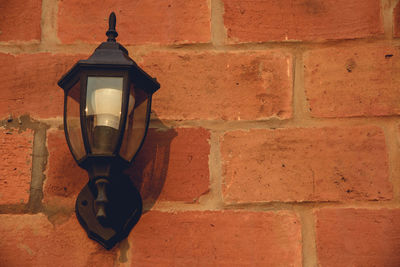 Close-up of lamp against brick wall