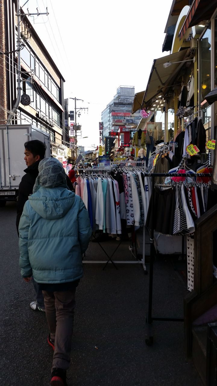 REAR VIEW OF MAN WALKING ON STREET