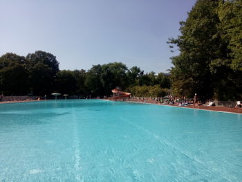 Swimming pool by trees against clear sky