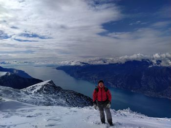 Full length of woman standing on snowcapped mountain against sky