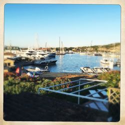 Boats moored in calm blue sea against clear sky