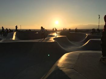 Silhouette people at skateboard park during sunset