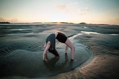 Woman doing back bend on beach