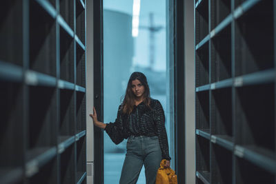 Portrait of young woman standing amidst shelves