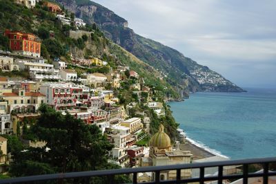 Scenic view of sea by mountains against sky