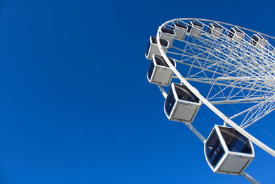 Low angle view of ferris wheel against clear blue sky