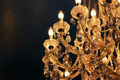 Low angle view of illuminated chandelier hanging from ceiling