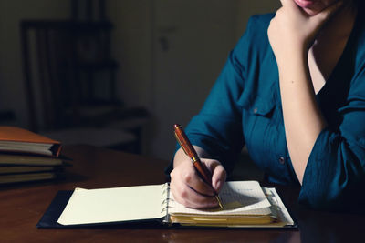 Midsection of woman reading book on table