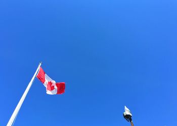 Low angle view of canadian flag waving against blue sky