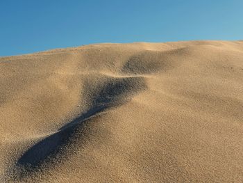 Sand dunes in desert against clear blue sky