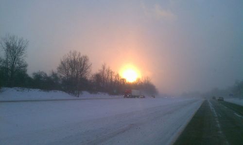 Snow covered road passing through field