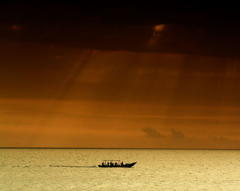 Silhouette of boat sailing in sea at sunset