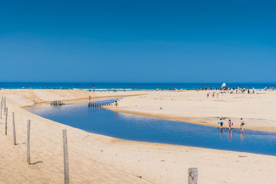 People on beach against blue sky