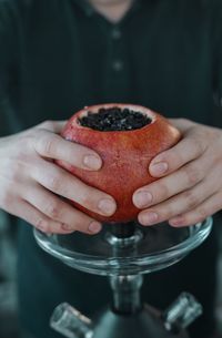 Midsection of man holding pomegranate on hookah