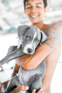 Smiling shirtless man standing with dog