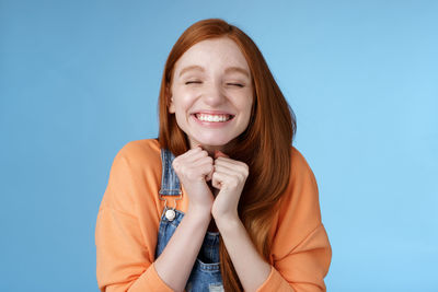 Excited young woman against blue background