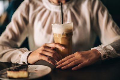 Midsection of woman holding drink on table